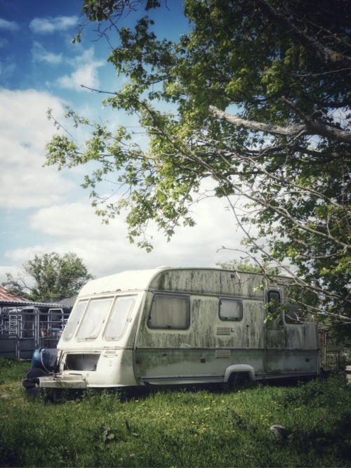 Decaying caravan and rusty farm sheds